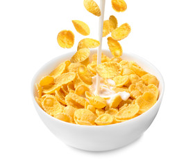 Pouring milk into bowl with corn flakes on white background. Breakfast cereal