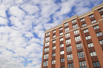 Facade part of modern residential apartment building against cloudy blue sky