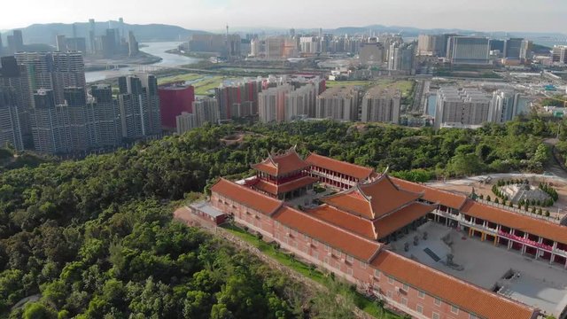Rotating aerial view of A-Ma Temple with Macau cityscape in background