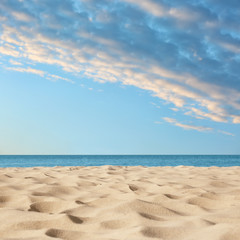 Fototapeta na wymiar Sandy beach near sea under blue sky with clouds