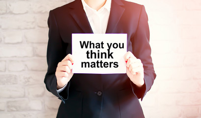 woman showing white card with WHAT YOU THINK MATTERS word . Business