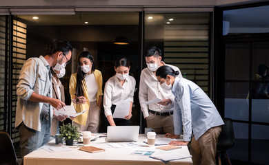 Six asian people work late at night wearing flu mask show new normal in work place