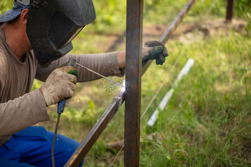 Worker installs a metal fence in the summer.