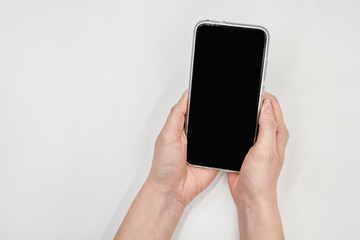 Mockup smartphone blank screen in female hands on light background. Closeup.