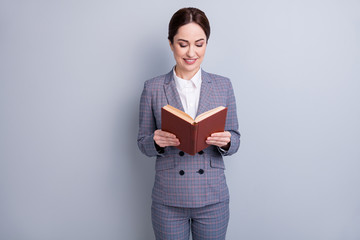Portrait of her she nice attractive focused knowledgeable intellectual skilled cheerful teacher wearing casual checkered suit reading academic dictionary isolated grey pastel color background