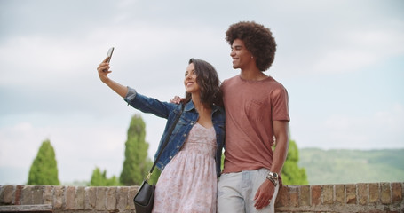 Romantic couple taking a selfie with smartphone in rural town of Assisi.approach wide shot.Friends...