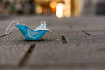 Health care and protection from COVID-19 concept, A piece of blue surgical mask thrown away on the...