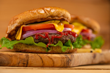 Hamburger or burger on a wooden background close-up, high-calorie food, home cooking