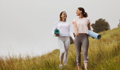 Women on a morning walk holding yoga mats