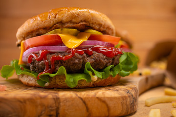Hamburger or burger on a wooden background close-up, high-calorie food, home cooking