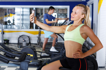 Fototapeta na wymiar happy female athlete taking selfie during training in fitness center