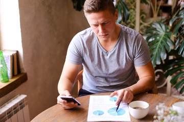 Young businessman working with documents and smartphoneat cafe.