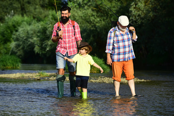 Grandfather, father and boy fishing together. 3 men fishing on river in summer time. Young - adult concept.