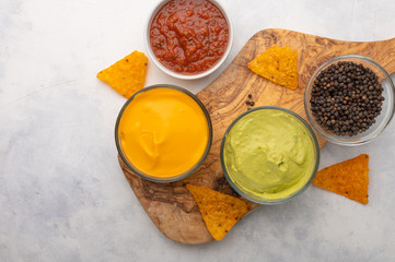 Chips and snacks with dips and salsa, and spices, top view on white background