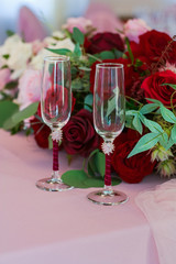 Glass glasses for newlyweds are decorated with a red ribbon