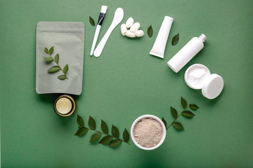 Frame made of set natural cosmetic products in white mockup packaging on green background. Beauty skincare hair treatment cosmetic moisturizer cream face mask silkworm cocoons. Flat lay Copy space
