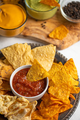 Chips with different snacks with salsa on a light background, close up