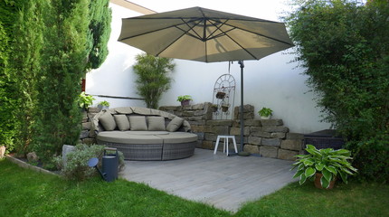 Gartenterrasse mit Loungegruppe und Sonnenschirm in einer Gartenecke mit Säulen-Faulbaum und...