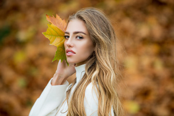 Young woman with autumn leaves in hand and fall yellow maple.