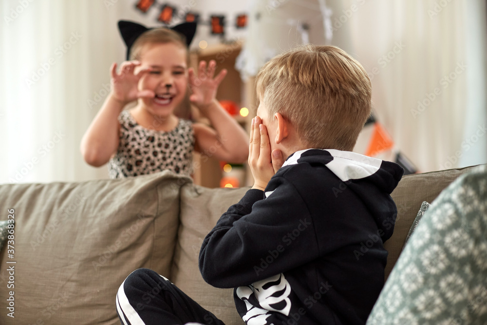 Poster halloween, holiday and childhood concept - smiling little boy and girl in costumes having fun at hom