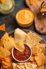 Different types of chips with dressings and dip and salsa, close-up, rest with beer, snacks