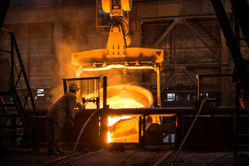 Steelworker at work near the tanks with hot metal - 373868352
