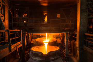 Fototapeta na wymiar Steelworker at work near arc furnace and pouring liquid metal 
