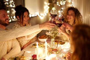 holidays, celebration and people concept - happy friends having christmas dinner at home drinking non-alcoholic red wine