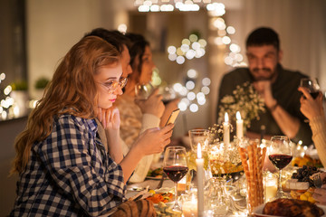 holidays and people concept - woman with smartphone at dinner party with friends at home