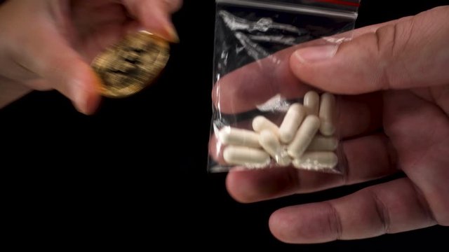 Bitcoin BTC cryptocurrency being used to buy black market drugs, a small transparent bag filled with pills black background 4k