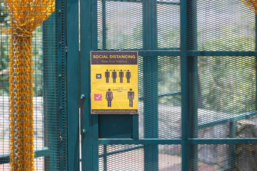 A poster placed at nearly all doors and gate at commercial outlet to remind people on social distancing requirement.
