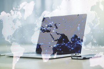 Abstract creative world map on modern laptop background, international trading concept. Multiexposure