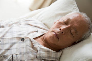 介護ベッドで眠るシニア男性の手元