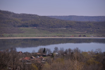 a lake in the village in spring season mirroring the big forest