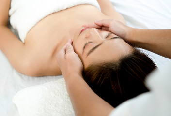 Obraz na płótnie Canvas Closeup face of a beautiful Asian woman to face massage in the spa. Beauty health concept