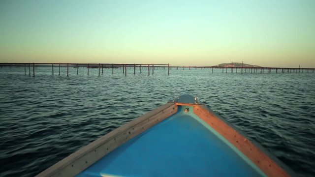 Une barque de p&ecirc;che de l'&eacute;tang de Thau navigue entres les parcs &agrave; hu&icirc;tres , couch&eacute; de soleil, on aper&ccedil;oit S&egrave;te.