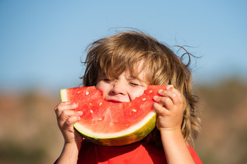 Kids with hungry face eating red watermelon in mouth. Child eat melon.