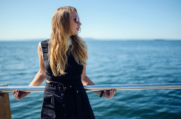 Woman in dress enjoys sea on the pier.
