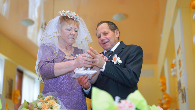 elderly old wife and hasband change golden rings in wedding anniversary