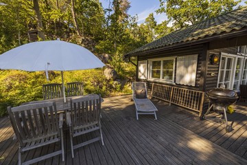 Obraz premium Beautiful view of wooden patio of private house on green trees background. Vacation concept. 