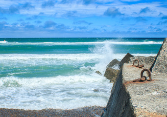 views of the sea to the horizon and waves crashing against the stone pier