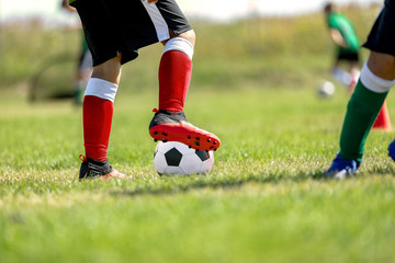 Child training soccer on fresh grass pitch. Soccer sports camp for kids. Boys practice dribbling in a field. Player develop dribbling skills. Boy in sportswear training with ball
