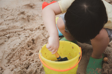 3 years old asian kid play sand on the beach. Background for family life and education. holiday with children.