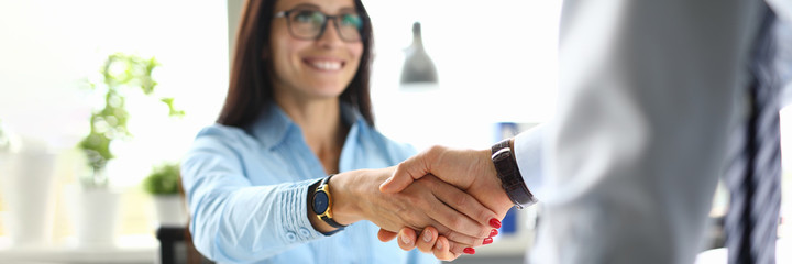 Business woman in office shakes hands with business partner. Mutually beneficial cooperation concept - obrazy, fototapety, plakaty