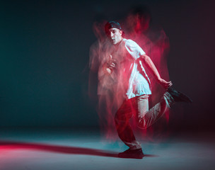 Stylish young guy breakdancer dancing hip-hop in neon light. Dance school poster. Long exposure shot