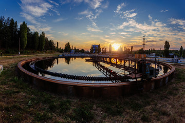 Modern sewage treatment plant. Round wastewater purification tanks at sunset.