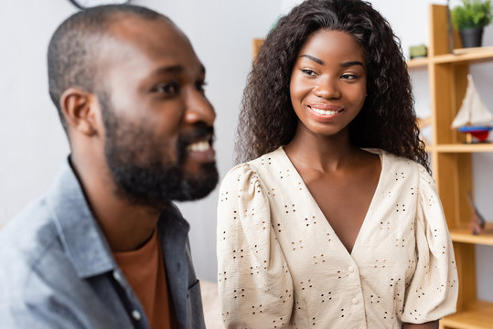 selective focus of african american woman in blouse looking at husband at home