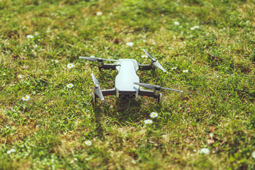 schräg von oben Ansicht eines im Gras liegenden weißen Quadrocopter