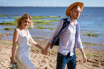 young couple in love walks on the beach against the background of the sea