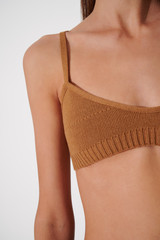 Skinny caucasian girl in brown woolen bra. Closeup woman's tanned body. Slim girl in good shape on the white background.